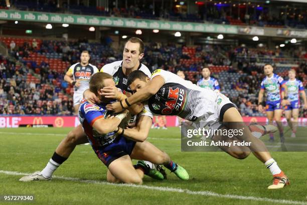 Nathan Ross of the Knights scores a try while tackled by the Panthers defence during the round 10 NRL match between the Newcastle Knights and the...