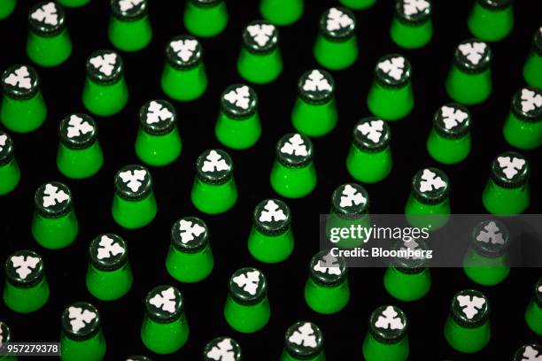 Logo sits on the top caps of green bottles of Carlsberg beer as they move along the production line following the labeling process at the Baltika...