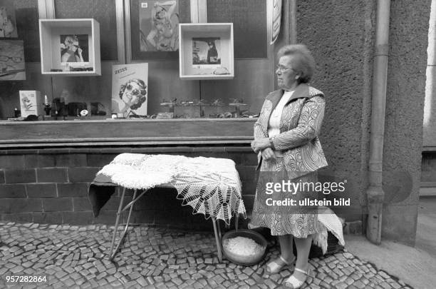 Eine alte Frau bietet auf einem Flohmarkt in Gerbstedt handgefertigte Häkeldeckchen an, aufgenommen im Mai 1984. Sie hat ihren Stand dabei vor dem...