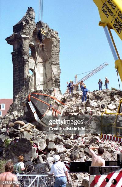 Ein großes Trümmerstück wird mit einem Kran an der Ruine der Frauenkirche in Dresden geborgen, an der die Sicherungsarbeiten und die Beräumung...