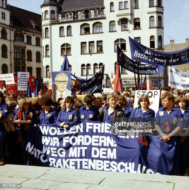 Mitglieder der Freien Deutschen Jugend im Blauhemd tragen ein Bildnis von Erich Honecker und Transparente mit Friedens-Losungen , aufgenommen im...