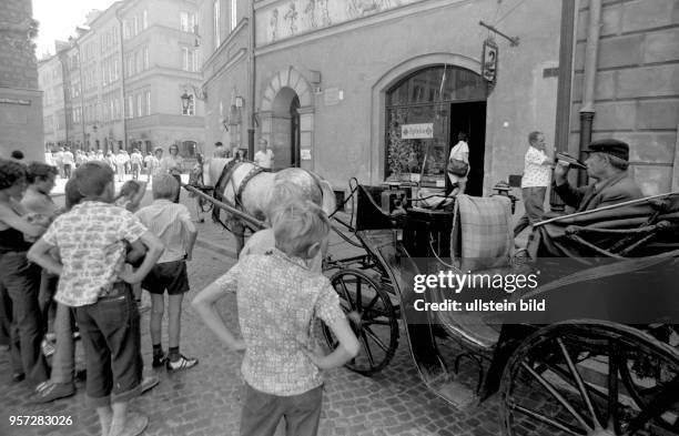 Kinder blicken auf eine Pferdekutsche in der Warschauer Altstadt, aufgenommen 1975 in Polen.