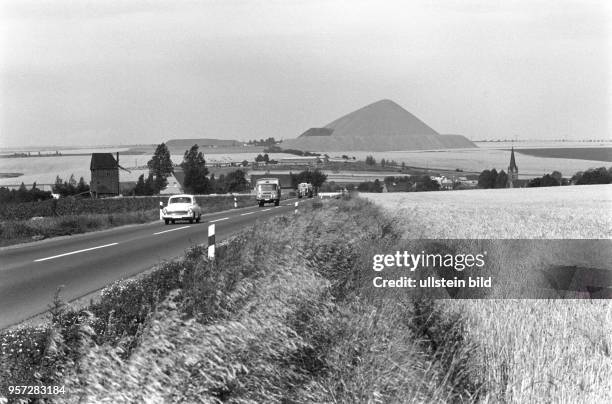 Fahrzeuge fahren auf einer Straße, die entlang eines Getreidefeldes führt, aufgenommen am bei Polleben im Mansfelder Land. Im Hintergrund ist eine...