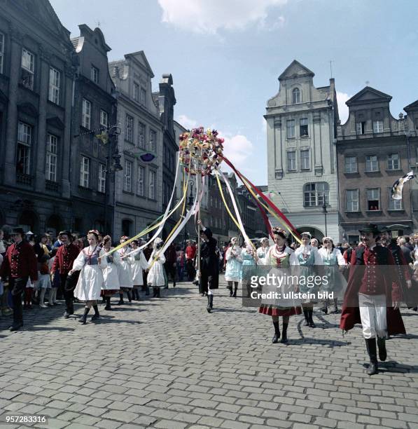 Volksfest zu Pfingsten in der Altstadt von Posen. Junge Männer und Frauen in traditionellen Kostümen nehmen am an einem Festumzug teil.