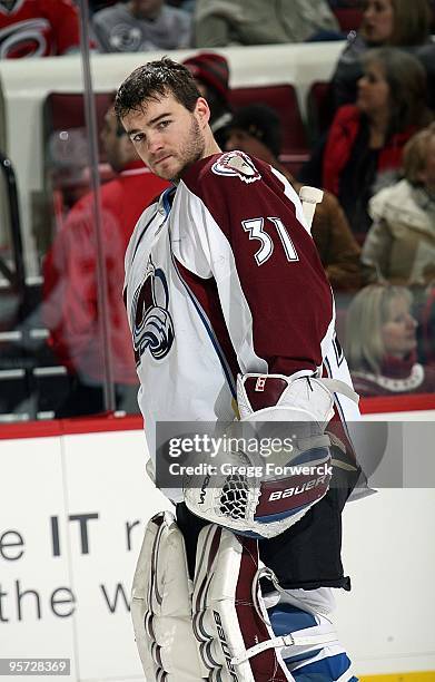 Peter Budaj of the Colorado Avalanche looks back to see if a replacement helmet is in sight during a NHL game against the Carolina Hurricanes on...