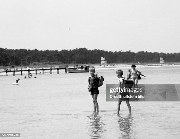 Zwei Jungs mit Schulranzen laufen durch das flache Wasser der Ostsee am Strand von Glowe auf der Insel Rügen, aufgenommen im Juni 1968.
