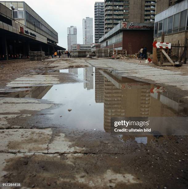 Eine große Pfütze auf einem provisorischen Gehweg zwischen Plattenbauten im Neubaugebiet Halle-Neustadt, undatiertes Foto von 1982.