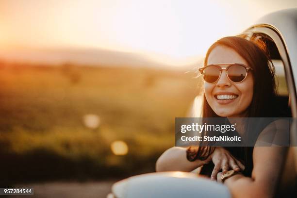 cute young woman hanging her head from a car - summer driving stock pictures, royalty-free photos & images
