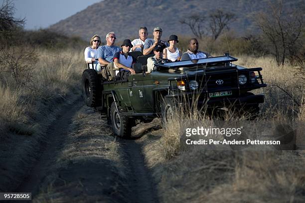 Tourists ride on a game drive as the sun sets in the Madikwe game reserve on September 11 in Madikwe, South Africa. The lodge is community owned by a...