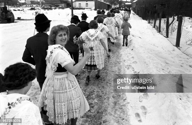 Junge Paare feiern bei kaltem Winterwetter die niedersorbische Fastnacht, genannt Zapust, am im Spreewald . Im Schneematsch sind sie zwischen den...