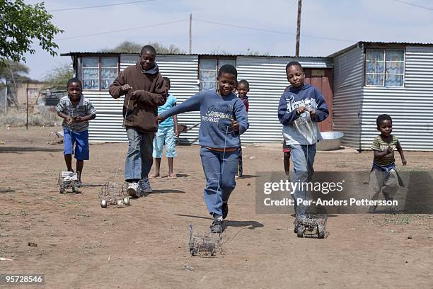 Children play with wire toy cars in Lekgophung village who owns the Buffalo Ridge game lodge in Madikwe game reserve on September 12 in Madikwe,...