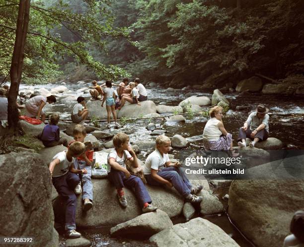 Kinder sitzen auf Steinen am Flussbett der Bode, aufgenommen 1985 bei Thale . Die Bode entspringt im Hochharz und mündet nach 169 km bei Nienburg in...