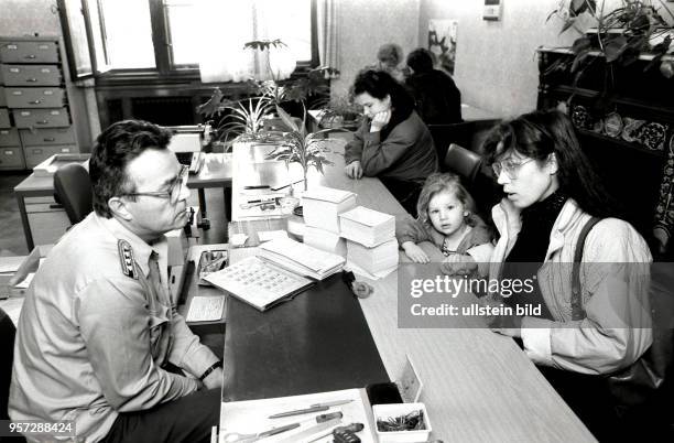 Eine Frau mit einem Kind steht in einem Meldeamt der DDR in Dresden in der Gotheallee einem hochrangigen DDR-Polizisten gegenüber, aufgenommen im...