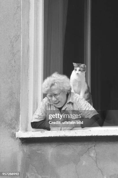 Eine ältere Frau schaut aus dem Fenster ihrer Wohnung in der Kastanienallee im Berliner Stadtbezirk Prenzlauer Berg, aufgenommen im Sommer 1989. Auch...