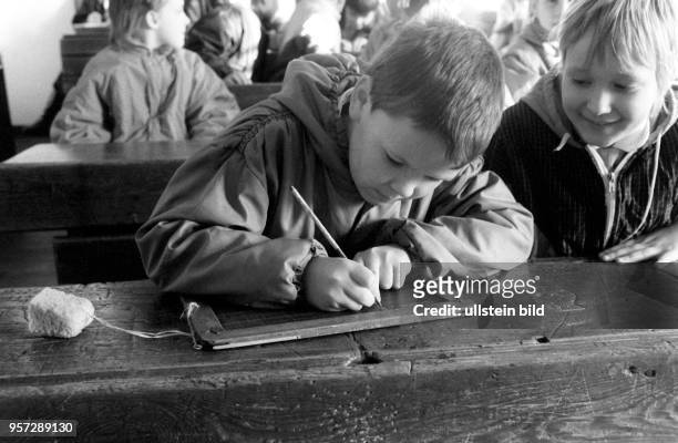 Eine Schulklasse besucht die zum Freilichtmuseum Schwerin-Mueß gehörende Dorfschule, aufgenommen im Februar 1989. Hier schreibt ein Schüler auf einer...