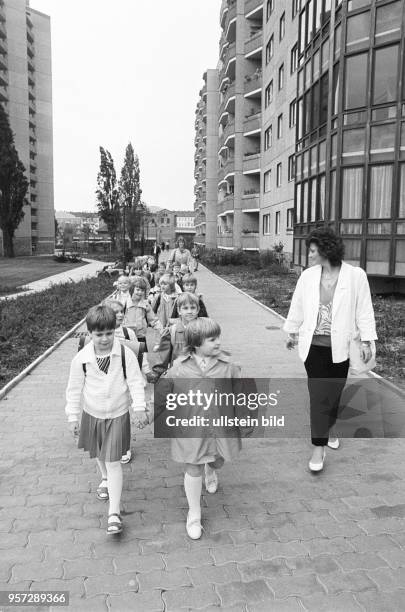 Mädchen und Jungen einer Schulklasse laufen Hand in Hand neben ihrer Lehrerin durch das neue Wohngebiet Ernst-Thälmann-Park in Berlin , aufgenommen...