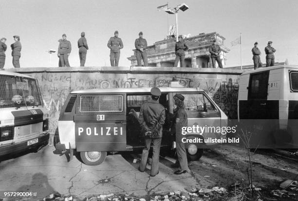 Soldaten der DDR-Grenztruppen stehen auf, Westberliner Polizisten vor der Berliner Mauer am Brandenburger Tor, aufgenommen am in Berlin. Zwei Tage...