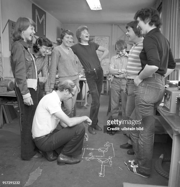 Junge Leute aus dem Klub Junger Physiker in Schipkau lachen über eine auf den Fußboden gezeichnete Schaltung, undatiertes Foto von 1981.