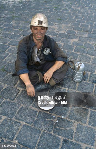 Ein Bergarbeiter sitzt vor einem Teller mit Geldmüntzen, undatiertes Foto von 1980. Mit der Wende wurde der unrentable Kupferbergbau im Mansfelder...