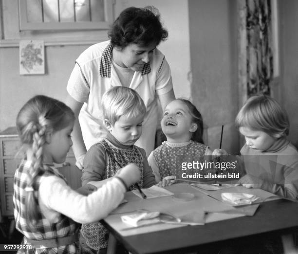 Kinder lernen in einem Kindergarten am Hochwald in Dresden mit viel Freude den Umgang mit dem Pinsel, aufgenommen 1970. Die Kindergärtnerin...