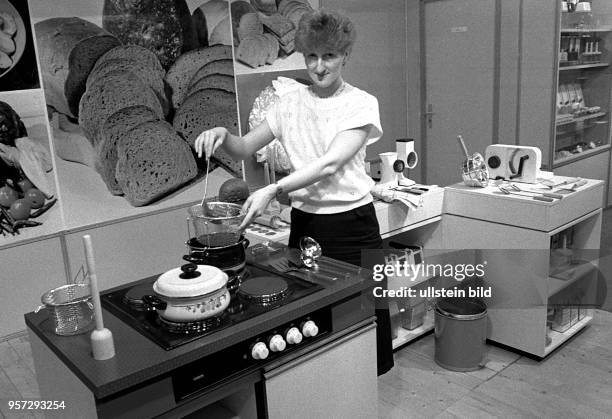 Eine Hostess demonstriert auf der Leipziger Messe einen Elektroherd und das dazu passende Geschirr aus DDR-Produktion, aufgenommen 1986. Konsumgüter...