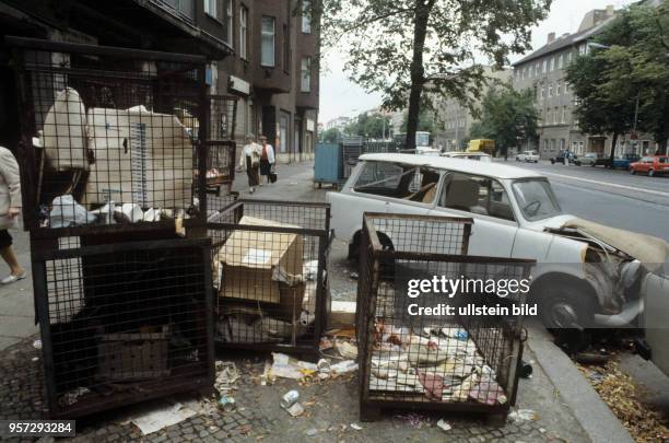 Ein kaputter Pkw Trabant und alte Metallcontainer mit Müll eines Handelsunternehmens stehen auf dem Gehweg der Brunnenstraße in Berlin-Ost,...