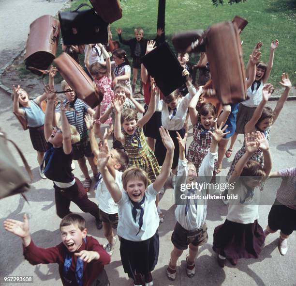 Lachend werfen Mädchen und Jungen einer Ost-Berliner Schule, das blaue Pionierhalstuch umgelegt, am letzten Schultag im Juli 1967 ihre Schultaschen...