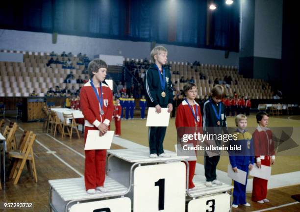 Kinder mit Medaillen und Urkunden auf dem Siegerpodest bei einer Siegerehrung bei der Kinder - und Jugendspartakiade der DDR 1979 in Berlin .