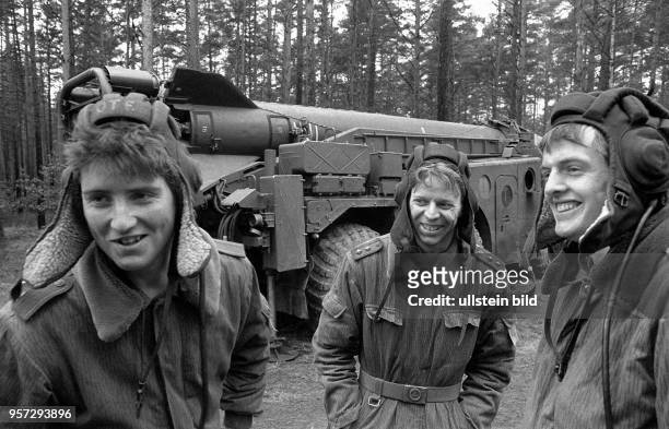 Soldaten der DDR mit Panzerhaube unterhalten sich vor einer Startrampe mit Rakete während einer Manöverübung der Flugabwehrraketentruppen,...