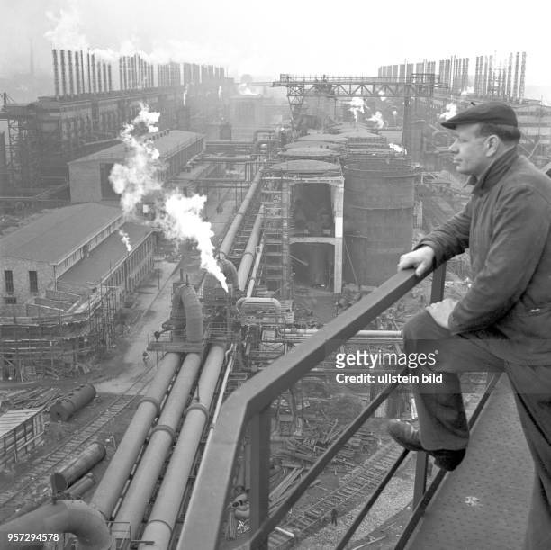 Ein Arbeiter blickt an einem Geländer auf das Gelände des VEB Braunkohleveredelung Lauchhammer, undatiertes Foto von 1960. In dem Großbetrieb wurde...