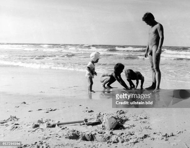 Ein Vater mit seinen Kindern am FKK-Strand bei Nonnewitz auf der Insel Rügen, aufgenommen im Sommer 1975. Ein Sommerurlaub an der Ostsee gehörte zu...