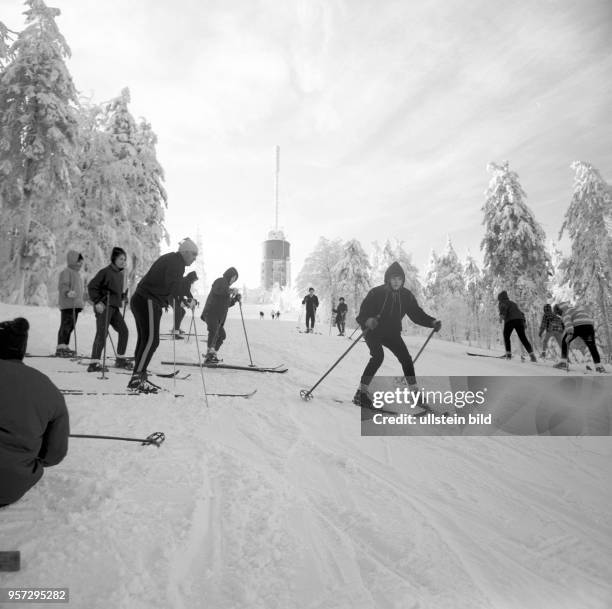 Skiläufer auf einem verschneiten Hang im Skigebiet am Großen Inselsberg bei Tabarz im Thüringer Wald, im Hintergrund der Sendeturm, aufgenommen im...