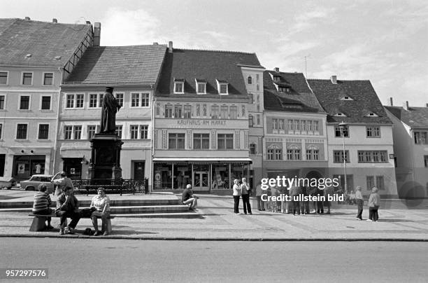 Passanten am Lutherdenkmal auf dem Markt in der Lutherstadt Eisleben laden zum Ausruhen ein, aufgenommen im August 1983. Eisleben ist Geburts-, Tauf-...