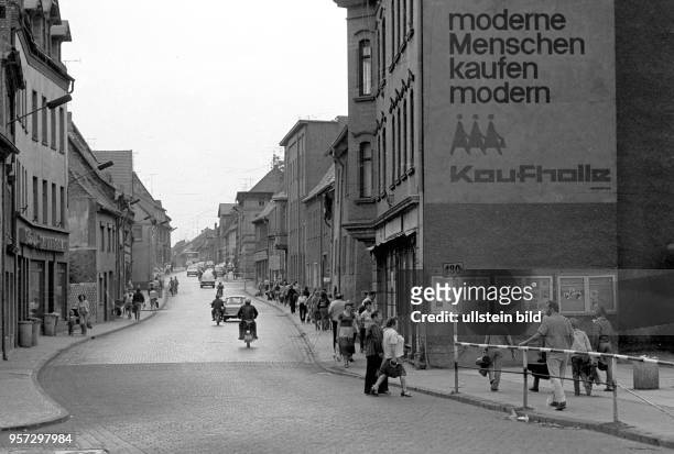 "Moderne Menschen kaufen modern" steht groß an einer Hausfassade in Eisleben, undatiertes Foto von 1982. Die Webrbung der HO bezieht sich auf den...