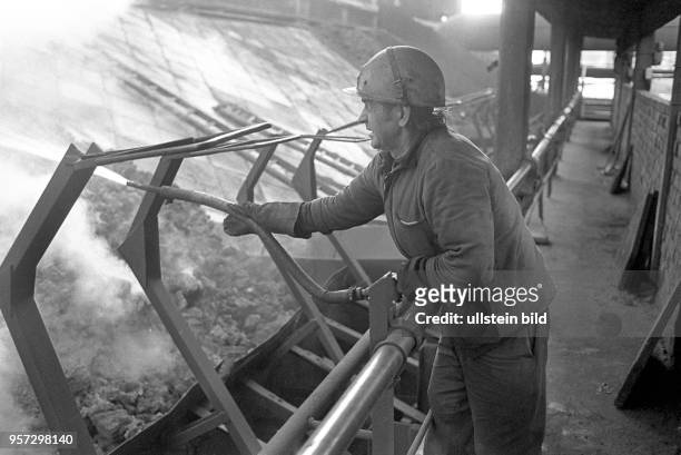 Ein Arbeiter löscht mit einem einem Wasserschlauch den schwelenden Koks an an der Koksrampe, aufgenommen 1979 im Gaswerk an der Dimitroffstraße/Ecke...