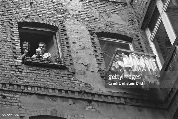 Eine junge Familie mit einem Kleinkind schaut aus dem Fenster einer Altbauwohnung in den Hinterhof eines Mietshauses in der Ackerstraße in...