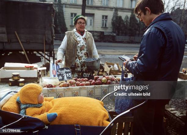 An einem Stand am Wochenmarkt in Berlin-Pankow kauft ein junger Mann mit Kinderwagen bei einem privaten Händler Äpfel 15 Mark pro Kilo, undatiertes...
