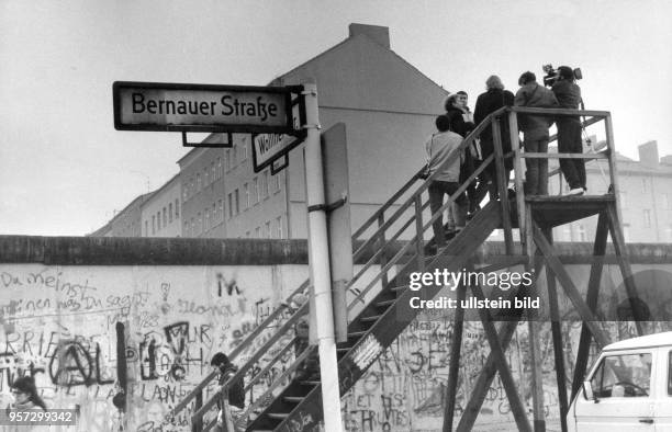 Auf einer hölzernen Aussichtsplattform an der Berliner Mauer an der geteilten Bernauer Straße/Ecke Wolliner Straße wird Ende November 1989 - wenige...