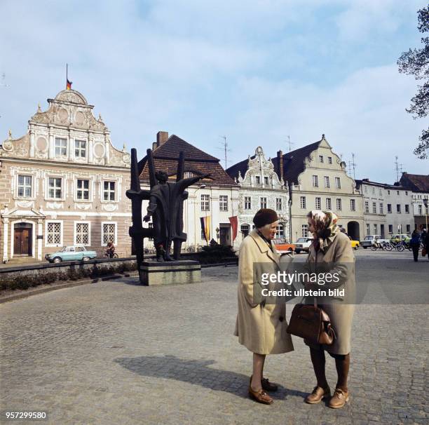 Zwei Frauen im Gespräch auf dem Marktplatz von Luckau in der Niederlausitz, im Hintergrund das Karl-Liebknecht-Denkmal und alte Bürgerhäuser,...