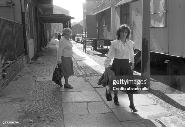 Eine ältere Frau schaut einer jüngeren, in Stöckelschuhen über den holprigen Gehwegbelag laufenden Frau hinterher, aufgenommen im Sommer 1985 in der...