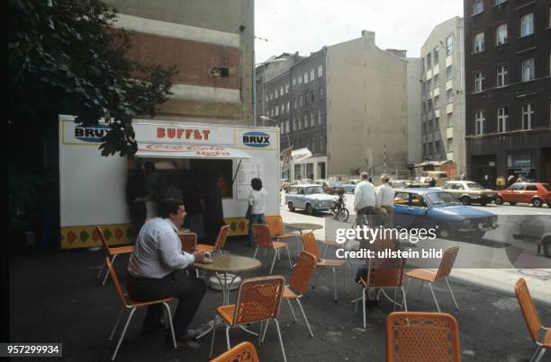 Vor einem Imbiss in der Brunnenstra0e in berlin-Ost sitzen Kunden, undatiertes Foto von 1990. Die Brunnenstraße verbindet die Berliner Ortsteile...