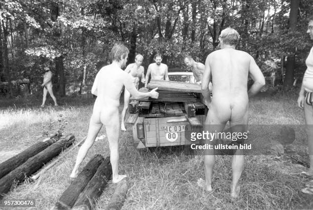 Männer laden Holzbohlen auf einen Pkw-Anhänger - Am Zeesener See in Senzig-Waldesruh liegt versteckt in waldreicher Gegend das über 60 Jahre alte...