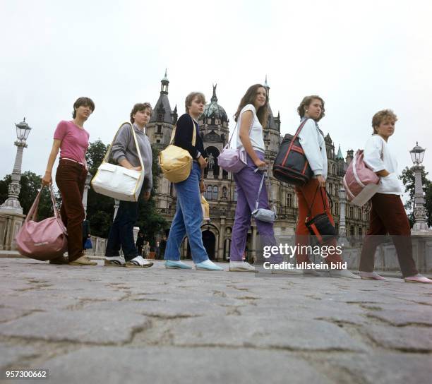 Frauen aus dem VEB Kombinat Lederwaren Schwerin zeigen vor dem Schweriner Schloss verschieden Produkte aus der Taschen-Produktion ihres Betriebes,...