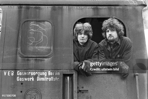 Zwei Arbeiter schauen aus der Dampflok der Werkbahn aufgenommen 1979 im Gaswerk an der Dimitroffstraße/Ecke Greifswalder Straße im Stadtbezirk...