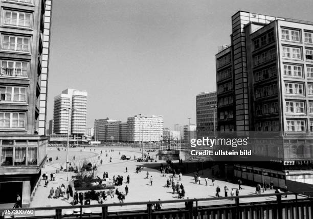 Menschen flanieren über den Berliner Alexanderplatz mit der von Erich John gestalteten Weltzeituhr, dem Alexanderhaus , dem Haus des Lehrers und dem...
