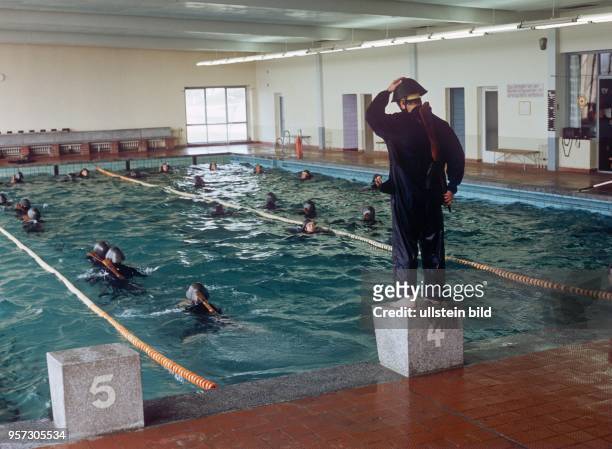 Ausbildung - schwimmen in Uniform, mit Stahlhelm und Waffe in der Schwimmhalle der Unteroffiziersschule "Egon Schultz" in Perleberg, undatierte Foto...