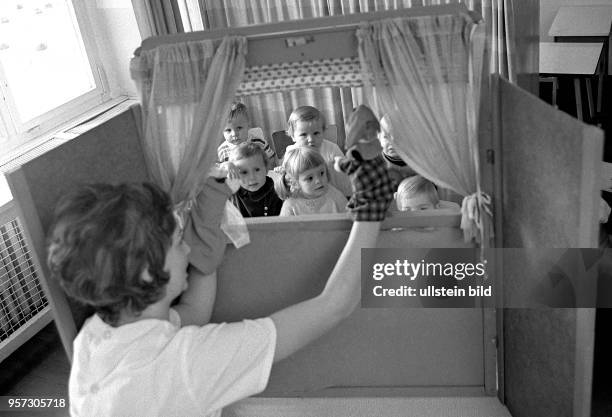 Eine Erzieherin veranstaltet für die Kinder einer Kinderkrippe in Dresden ein Puppentheater, aufgenommen 1975. Kinderkrippen waren...