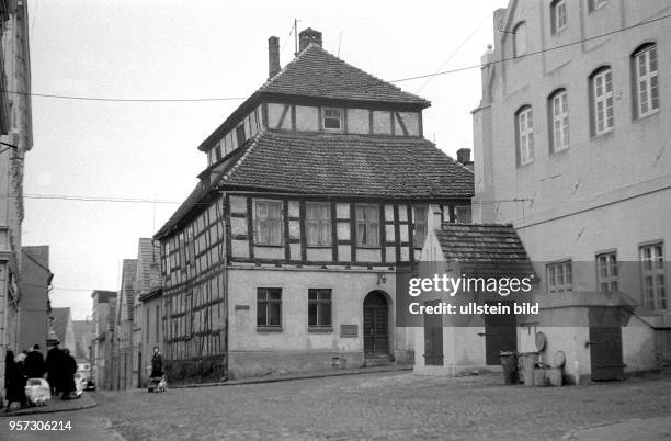 Blick in eine Straße mit Kopfsteinpflaster und einem Fachwerkhaus in der Stadt Wolgast an der Ostseeküste zur Insel Usedom, aufgenommen um 1960. Zwei...