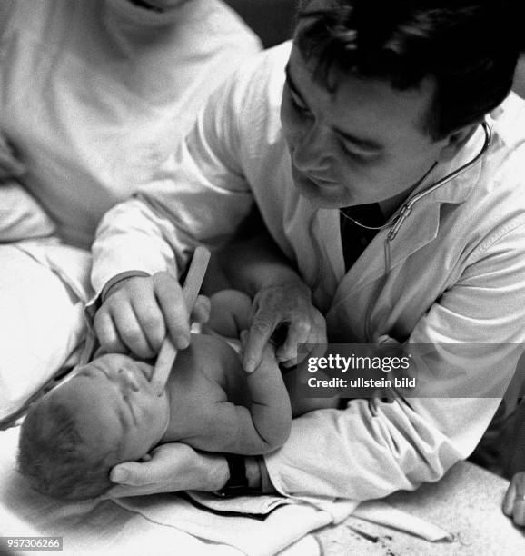 Ein Kinderarzt untersucht ein Neugeborenes in der Kinderklinik der Medizinischen Akademie Dresden, aufgenommen Anfang 1969.