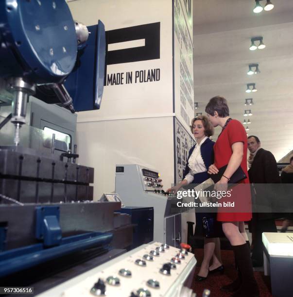 Eine Werkzeugmaschine aus Polen wird auf der Frühjahrsmesse in Leipzig von zwei Frauen begutachtet, aufgenommen im März 1970.